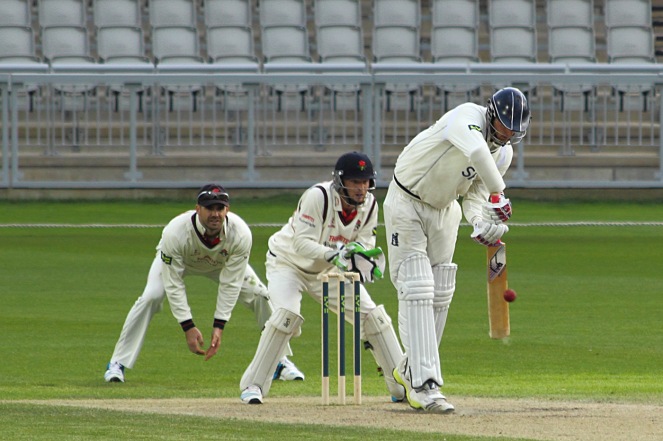 Lancashire-V-Warwickshire-county-cricket-match-2. Oliver Hannon-Dalby defends the ball as Jos Butler and Jimmy Anderson look on 
